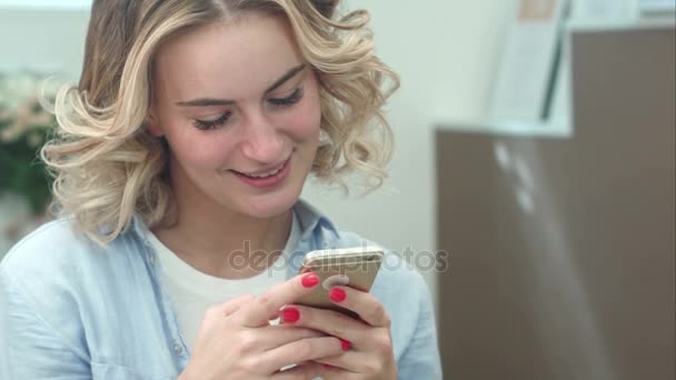 Mulher sorridente bonita mensagens de texto no smartphone no salão de beleza — Vídeo de Stock