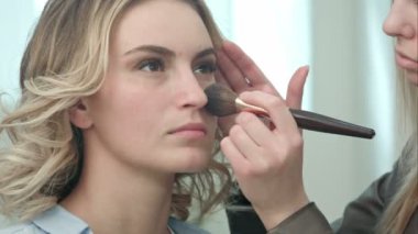 Profesyonel makyaj sanatçı toz genç modeli yüze uygulama