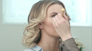 Güzel bir genç sarışın kız, makyaj yapıyor makyöz toz büyük fırça ile geçerlidir