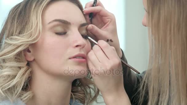 Artista de maquillaje aplicando maquillaje de pestañas al ojo modelo — Vídeo de stock