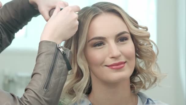 Manos de peluquero están haciendo pequeños rizos, hablando con una joven modelo — Vídeo de stock