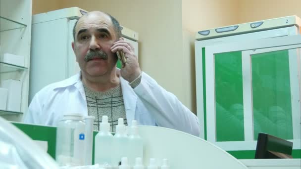 Улыбающийся старший фармацевт по телефону в аптеке — стоковое видео