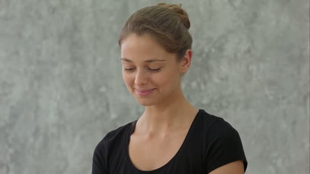 Joven entrenadora haciendo pose namaste y sonriendo, grupo de bienvenida antes de la clase de yoga — Vídeos de Stock