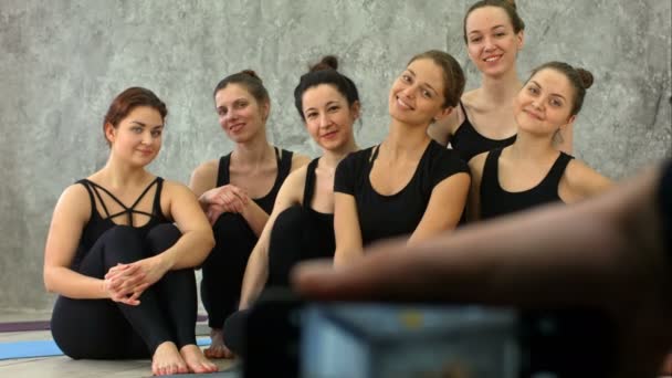 Mano masculina sosteniendo el teléfono inteligente tomando una foto del grupo de chicas en la clase de fitness en el descanso — Vídeos de Stock