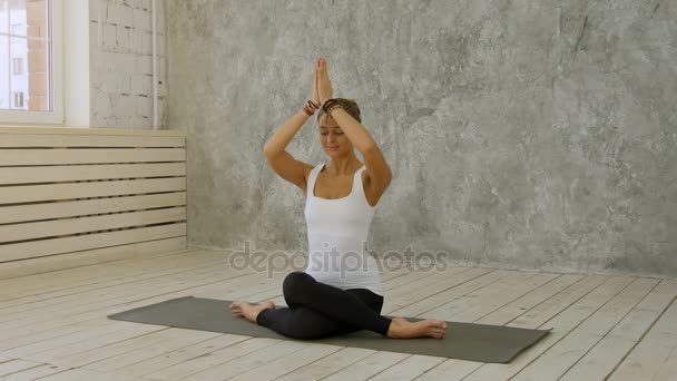 Portrait of beautiful smiling young woman working out indoors in loft interior doing Marichyasana pose with namaste gesture — Stock Video
