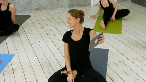 Porträtt av leende passar kvinna använda digitala surfplatta med videochatt medan du sitter på yogamattan efter fitnessutövaren — Stockvideo