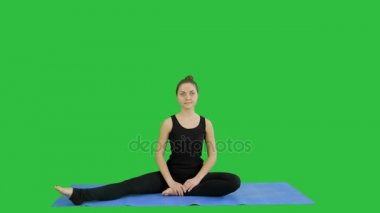 Genç kadın bir yeşil ekranında, Chroma Key yoga pratik yaparken bacaklarını germe