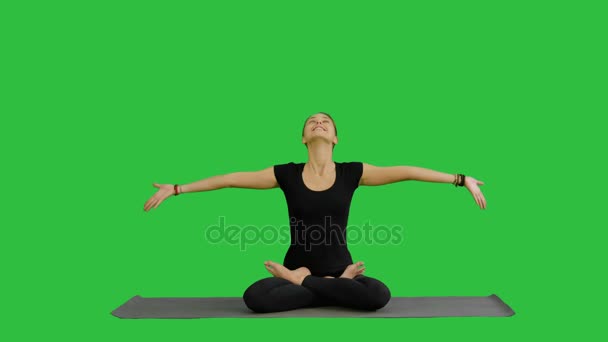 Ung kvinna mediterar samtidigt öva yoga på en grön skärm, Chroma Key — Stockvideo