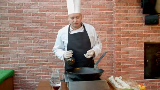 Шеф-повар наливает растительное масло в кастрюлю, разговаривает с камерой — стоковое видео