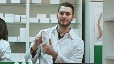 Genç malepharmacist bir beyaz boş kutu ilaç, tıp, meslektaşı çalışma sırasında teşvik tutarak