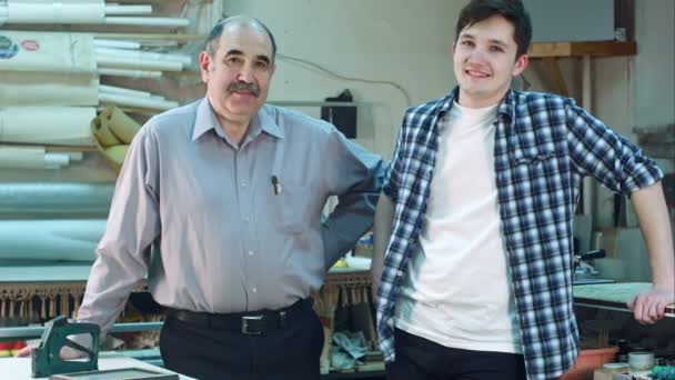 Retrato de dos trabajadores, de pie en el taller, sonriendo y mirando a la cámara — Vídeos de Stock