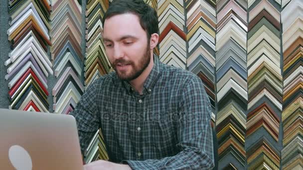Porträt eines jungen männlichen Geschäftsinhabers, der am Laptop hinter der Theke seines Geschäfts arbeitet — Stockvideo