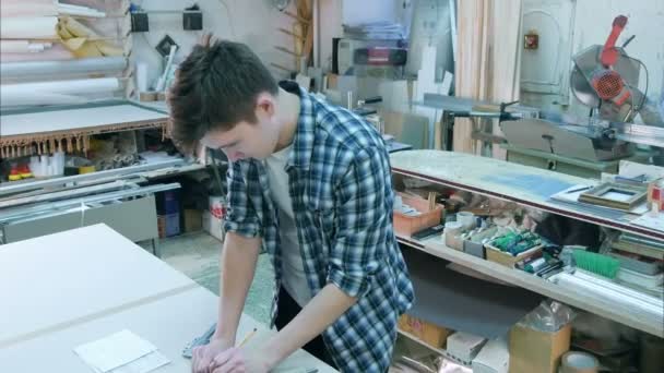 Portret młodego pracownika będącego mężczyzną za biurkiem konstruowania ramki w warsztacie — Wideo stockowe
