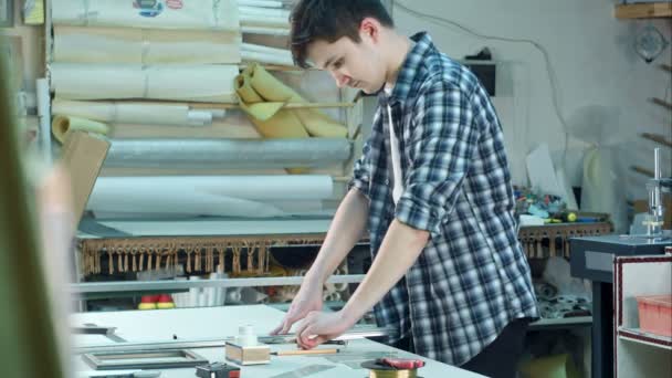 Jonge werknemers snijden het glas voor frame in frame werkplaats, plotseling zijn vinger snijden — Stockvideo