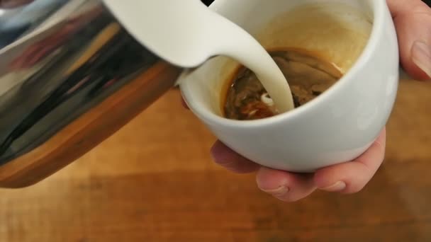 Derramando leite corrente em uma xícara de café expresso — Vídeo de Stock