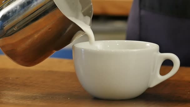 Verter leche de arroyo en una taza de café expreso para hacer café con leche — Vídeos de Stock