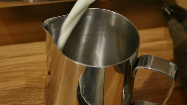 Barista wlewając mleko od duży słoik przezroczysty do dzbana metal mleko — Wideo stockowe