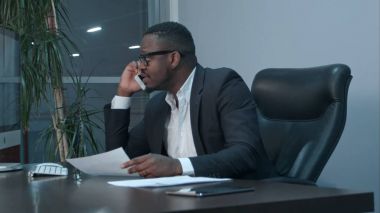 Grafikleri incelemek ve telefonda konuşurken Afro-Amerikan işadamı