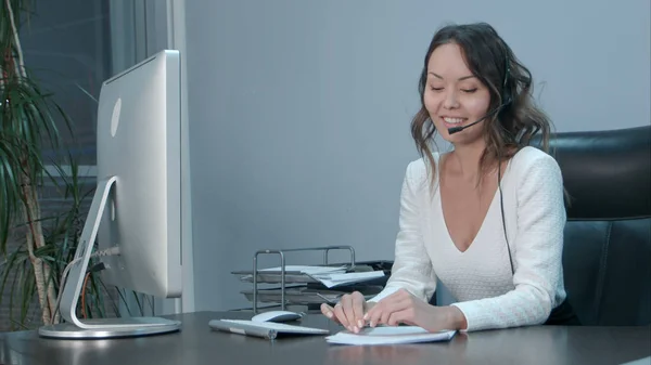 Joven asiático operador hablando con cliente en internacional call center — Foto de Stock