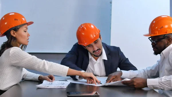 Colegas multirraciais lendo documentos de construção, discutindo-o — Fotografia de Stock