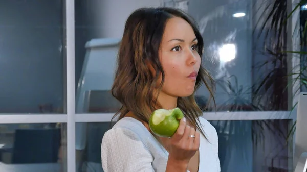 Bella donna d'affari mangiare mela verde in ufficio — Foto Stock