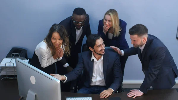 Retrato de equipe de negócios chocada pela mesa olhando para laptop no escritório — Fotografia de Stock