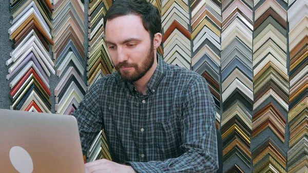 Portrait d'un jeune homme d'affaires travaillant sur un ordinateur portable derrière le comptoir de sa boutique — Photo
