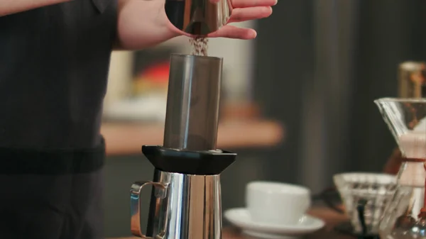 Бариста добавляет измельченный кофе и наливает горячую воду — стоковое фото