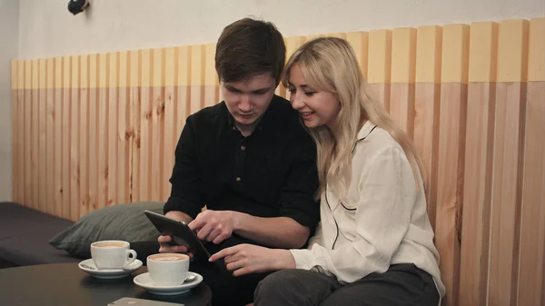 Pareja joven en un café, bebiendo café y usando tableta digital — Foto de Stock
