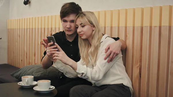 Lyckliga paret i ett kaffehus som äter frukost och och med mobiltelefon — Stockfoto