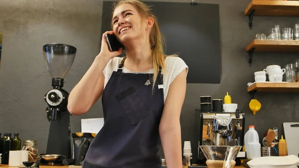 Молодая женщина звонит с мобильного телефона на рабочем месте — стоковое фото