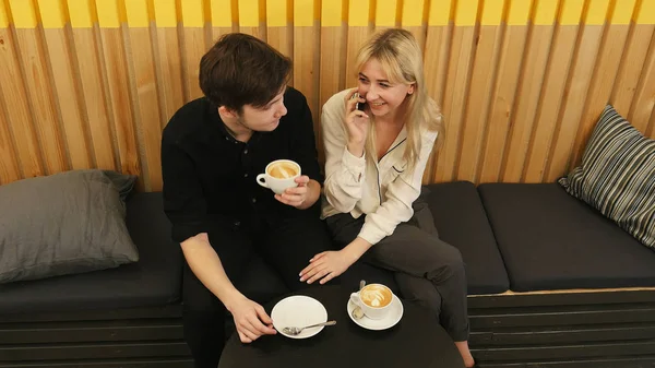 Junge, gut gelaunte Frau spricht per Handy, während sie sich im Coffeeshop verabredet — Stockfoto