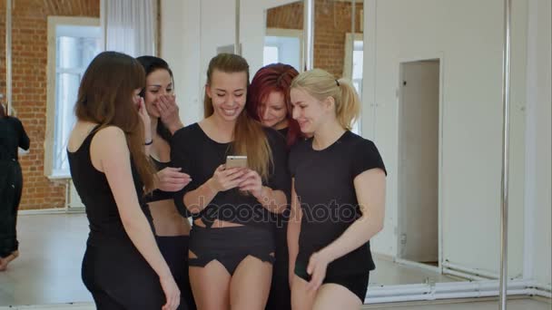 Cute happy dancerstaking a break from their workout and social networking with a cell phone — Stock Video