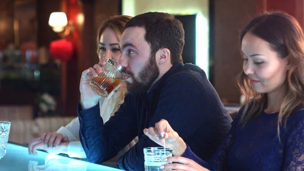 Empresário bêbado e cansado sentado no balcão no bar com duas jovens mulheres — Fotografia de Stock