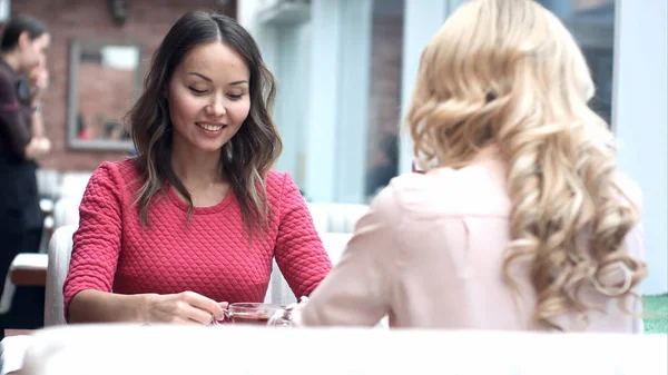 Kahve ile kentsel kafede oturan ve konuşurken iki genç güzel kız