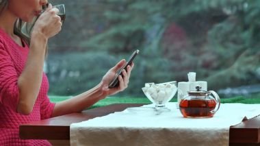 Cep telefonu kullaranarak ve kafede çay içme kadın