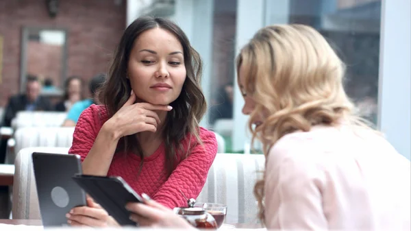 Duas mulheres bonitas no café usando tablet digital — Fotografia de Stock