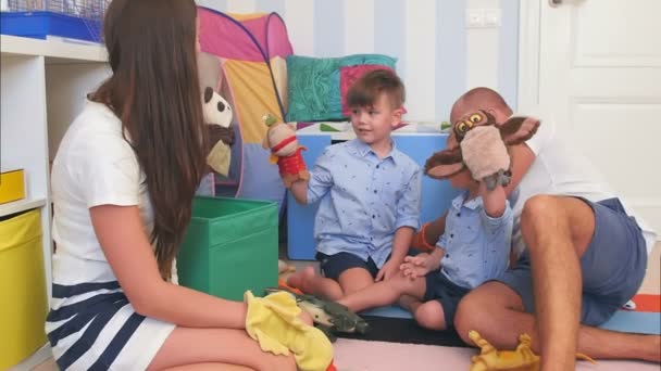 Счастливые родители и два маленьких мальчика играют с куклами — стоковое видео