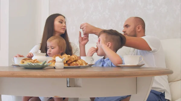 Szczęśliwa młoda rodzina korzystających herbaty ze słodyczami w restauracji lub w kawiarni lub w domu — Zdjęcie stockowe