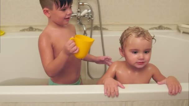 Litttle boy washing his younger brother in a bath — Stock Video