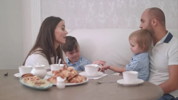 Joven mamá y papá divirtiéndose con dos hijos pequeños en la mesa de té —  Fotos de Stock