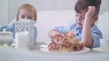İki sevimli küçük çocuklar eğleniyor pasta ile çay masasında