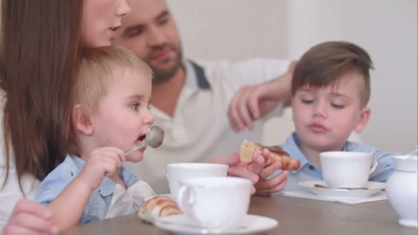 Dos niños pequeños tomando té con pastelería junto con sus padres — Vídeos de Stock