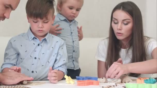 Unga lyckliga föräldrar visar sina barn hur man gör cookies — Stockvideo