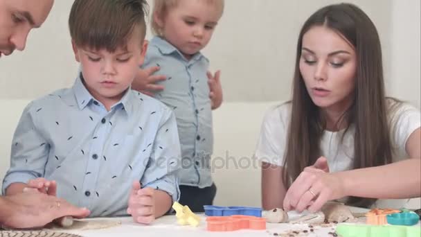 Jóvenes padres felices enseñando a sus hijos a hacer galletas — Vídeo de stock