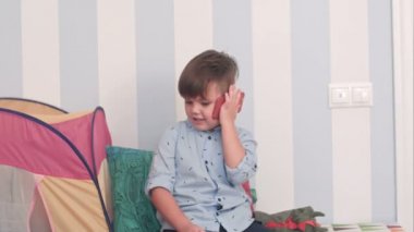 Küçük çocuk odasında cep telefonu konuşurken gülümseyen