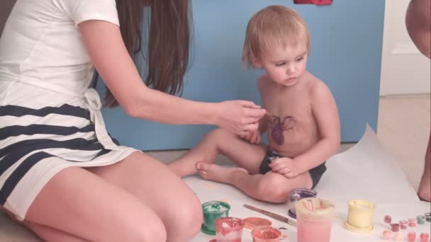 Mère peignant une araignée sur son petit garçon — Video