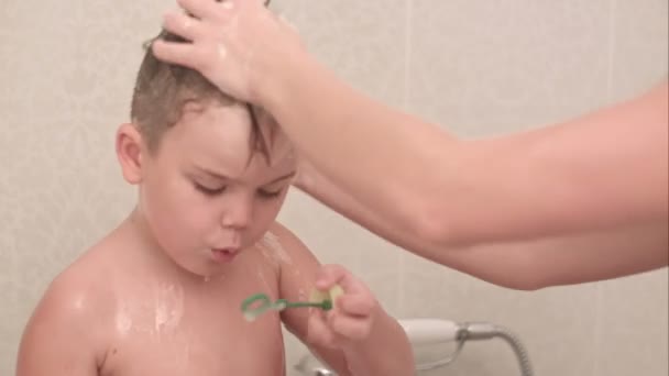 Mère laver son petit garçon dans le bain pendant qu'il souffle des bulles — Video