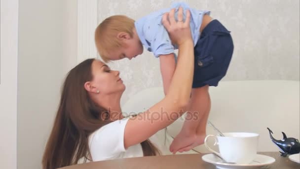 ティー テーブルのそばに座って彼女の男の子と一緒に遊んで幸せな若い母 — ストック動画