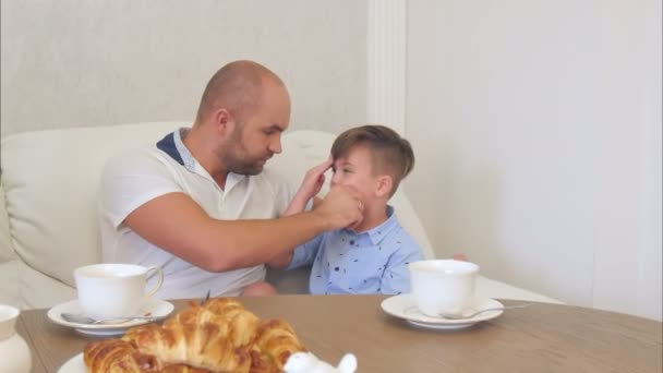 Junger Vater putzt seinem kleinen Sohn nach dem Mittagessen das Gesicht — Stockvideo